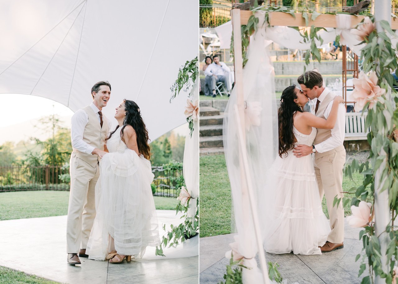  Bride and groom laugh together and kiss after first dance behind floral backdrop 