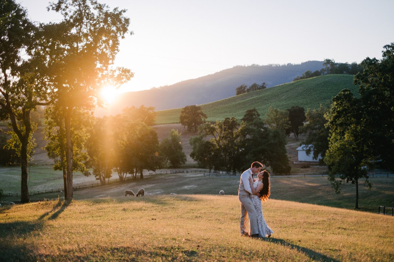  Golden hour sunset portrait of couple in field with sheep and green rolling hills in Roseburg valley 