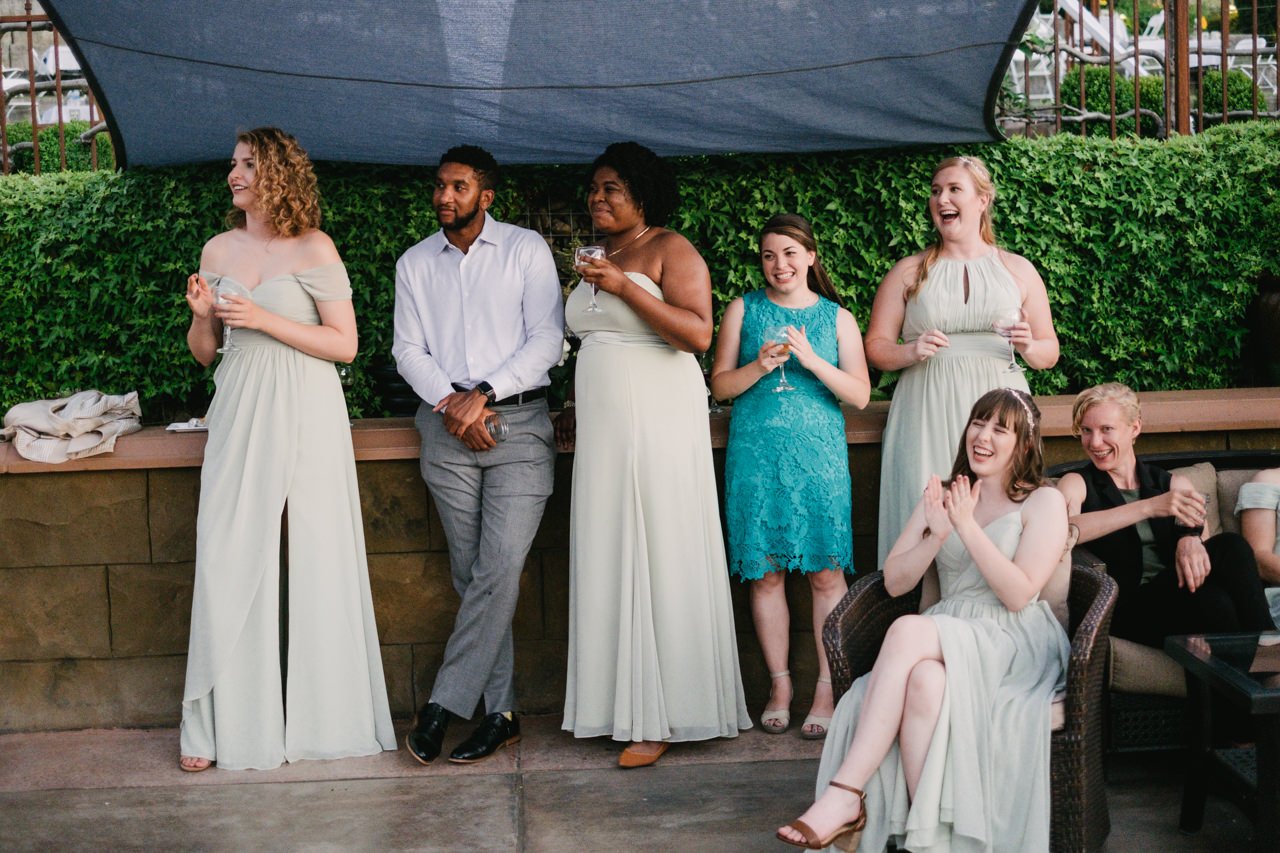  Wedding guests stand and sit close while laughing and listening 