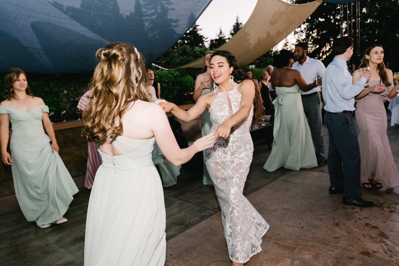  Bride dances with bridesmaid in light green dress under shades 