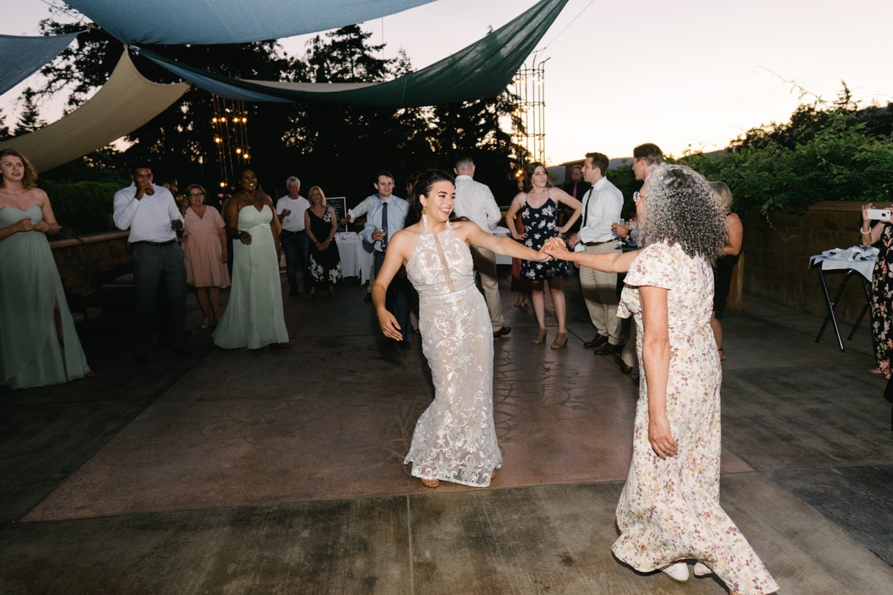  Bride and mother dance during dance at evening light 