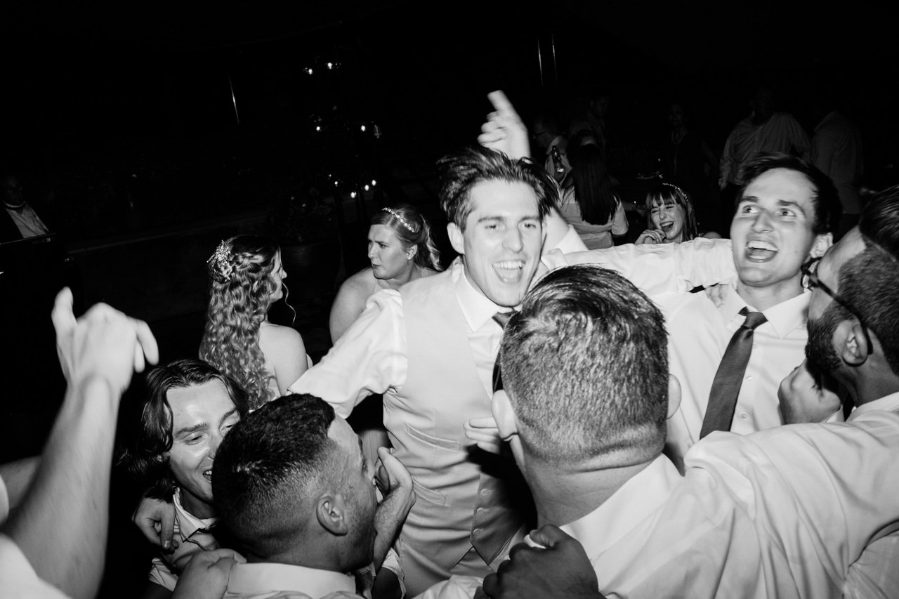  Groom in middle of dance party in black and white photo 