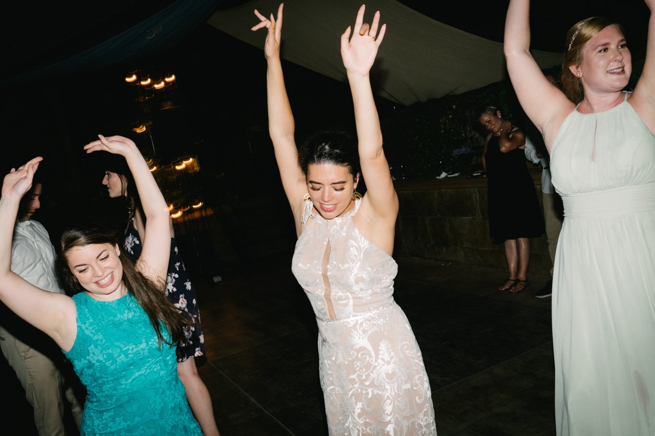  Bride and guests throw arms in air during dancing 