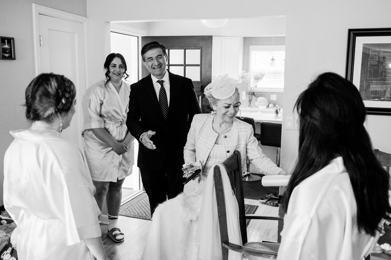  Brides parents laugh with bridesmaids in airbnb 