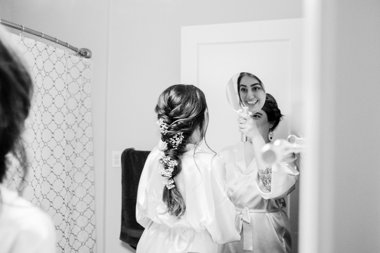  Bride smiles excitedly in mirror while looking at mirror 