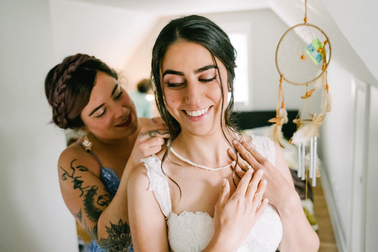  Bridesmaid latches necklace with dreamcatcher behind her 