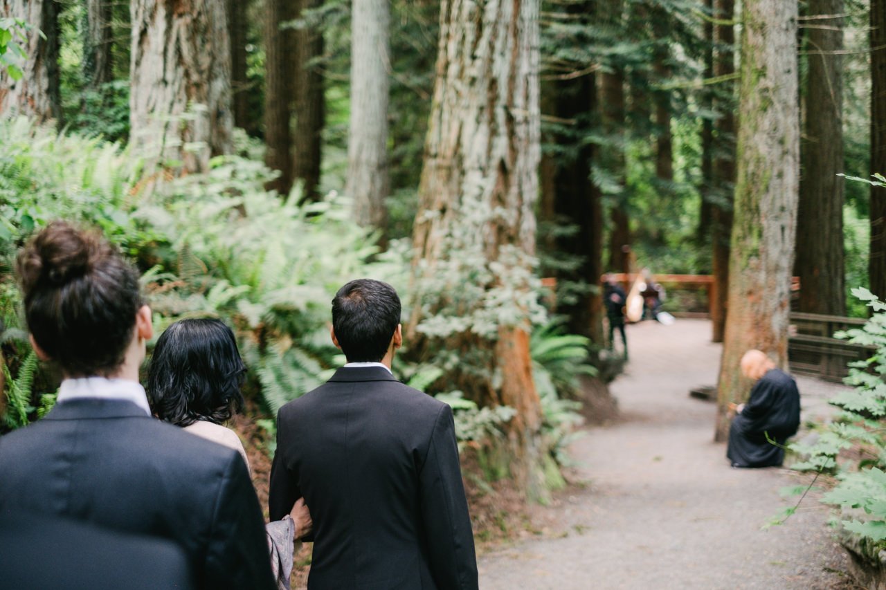  Groom waits with mother on forest park trail towards redwood deck 