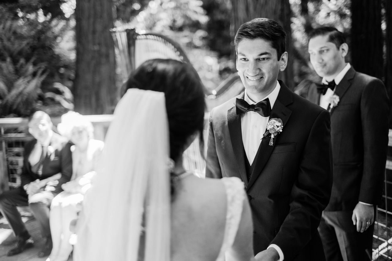  Groom in bowtie smiles at bride in black and white photo 