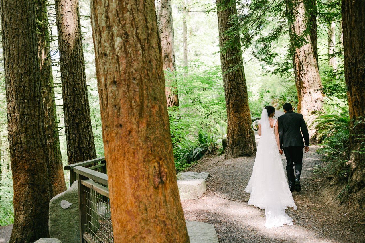  Wedding couple exits ceremony holding hands through redwood trees 