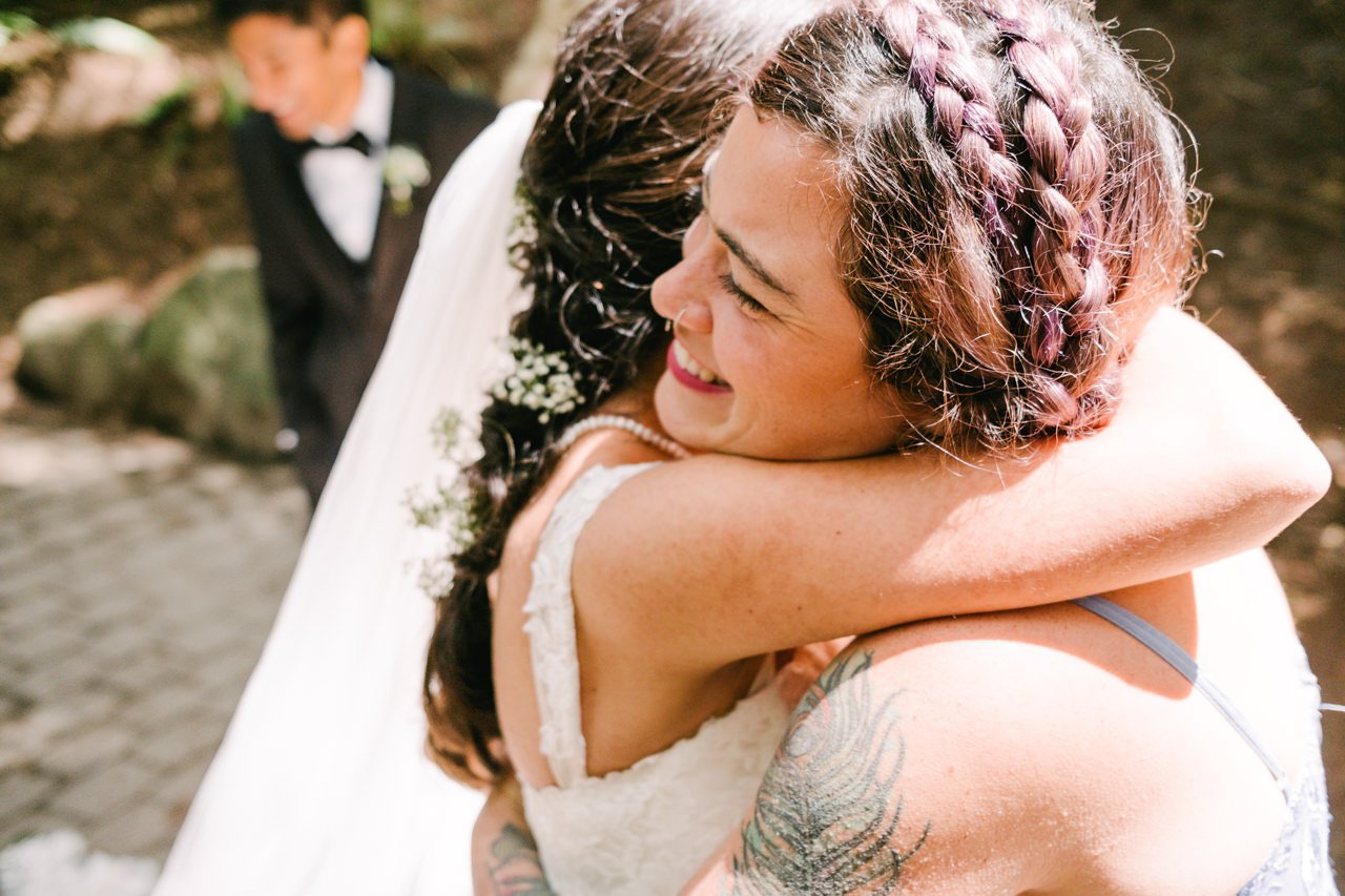  Bridesmaid with feather tattoo hugs bride 