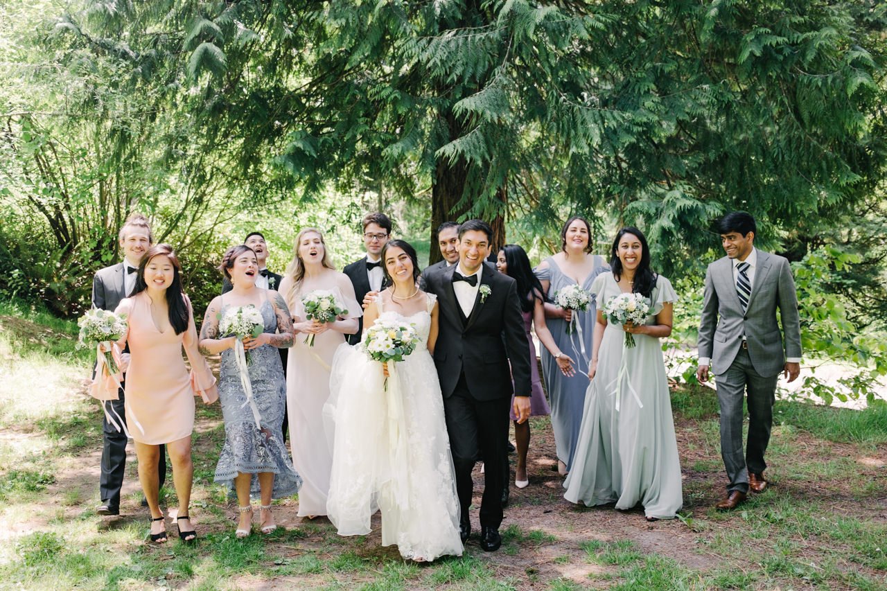  Wedding party walking and laughing casually in forest 