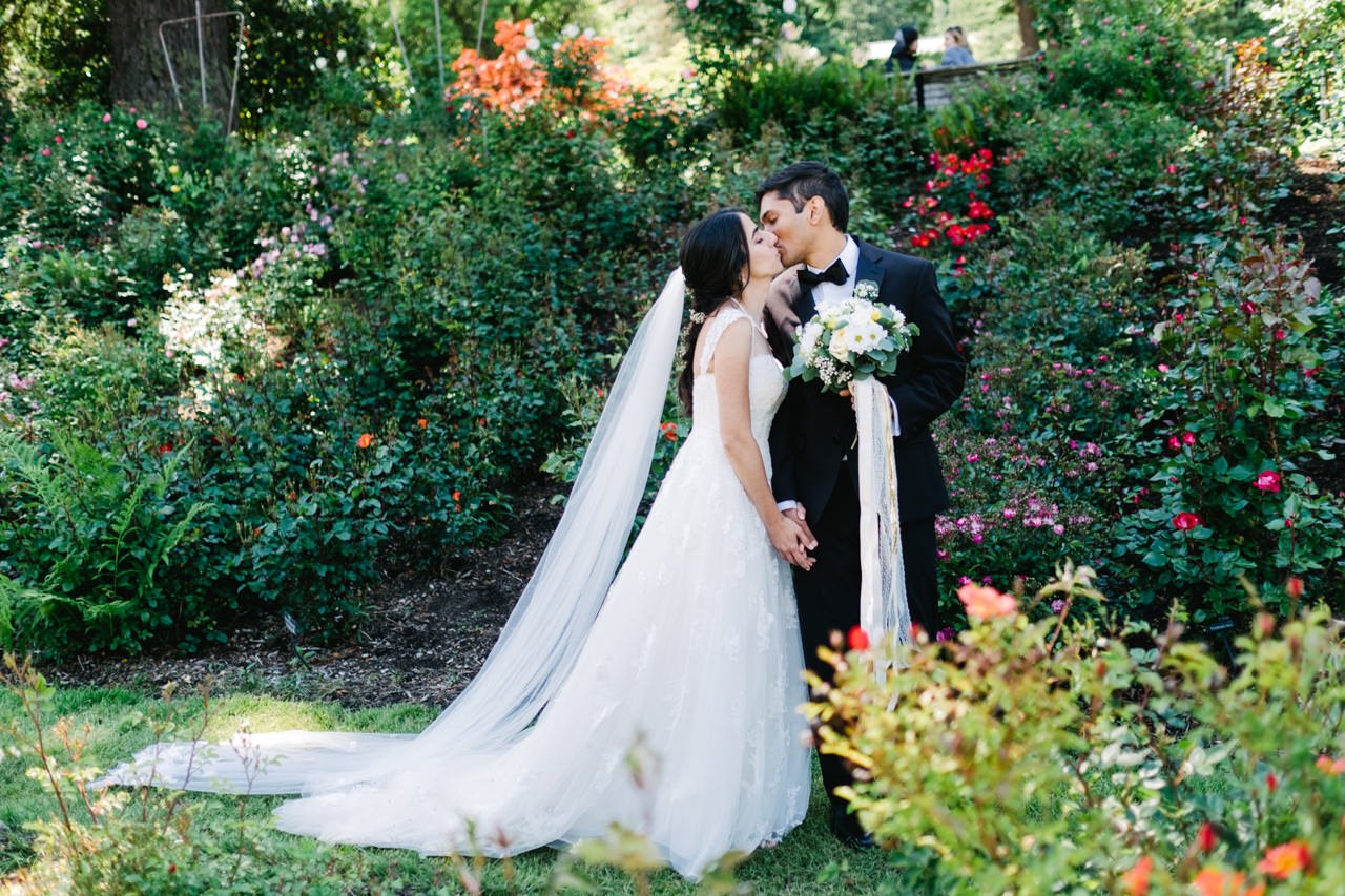  Indian couple kiss in rose garden in American wedding attire 