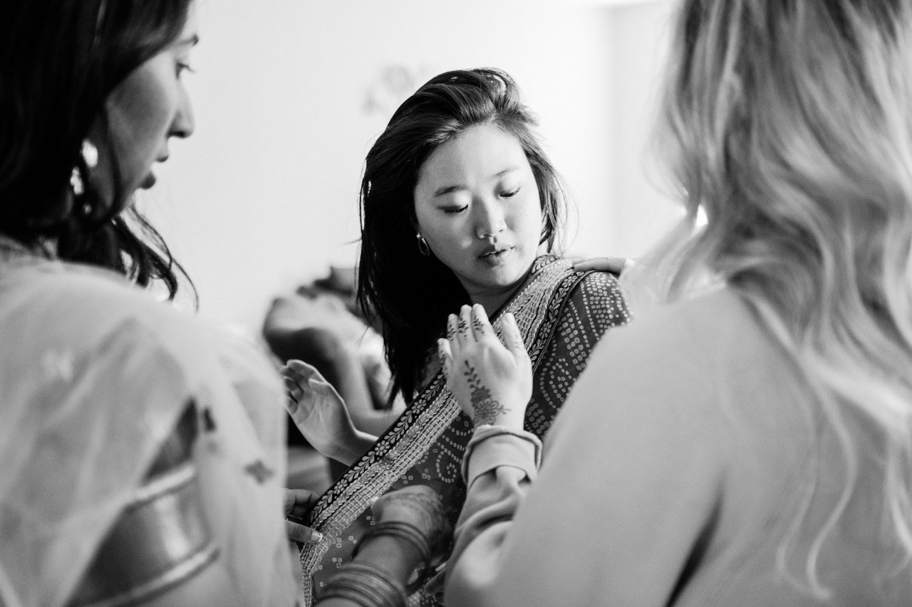  Bridemaid gets help adjusting sari in black and white photo 