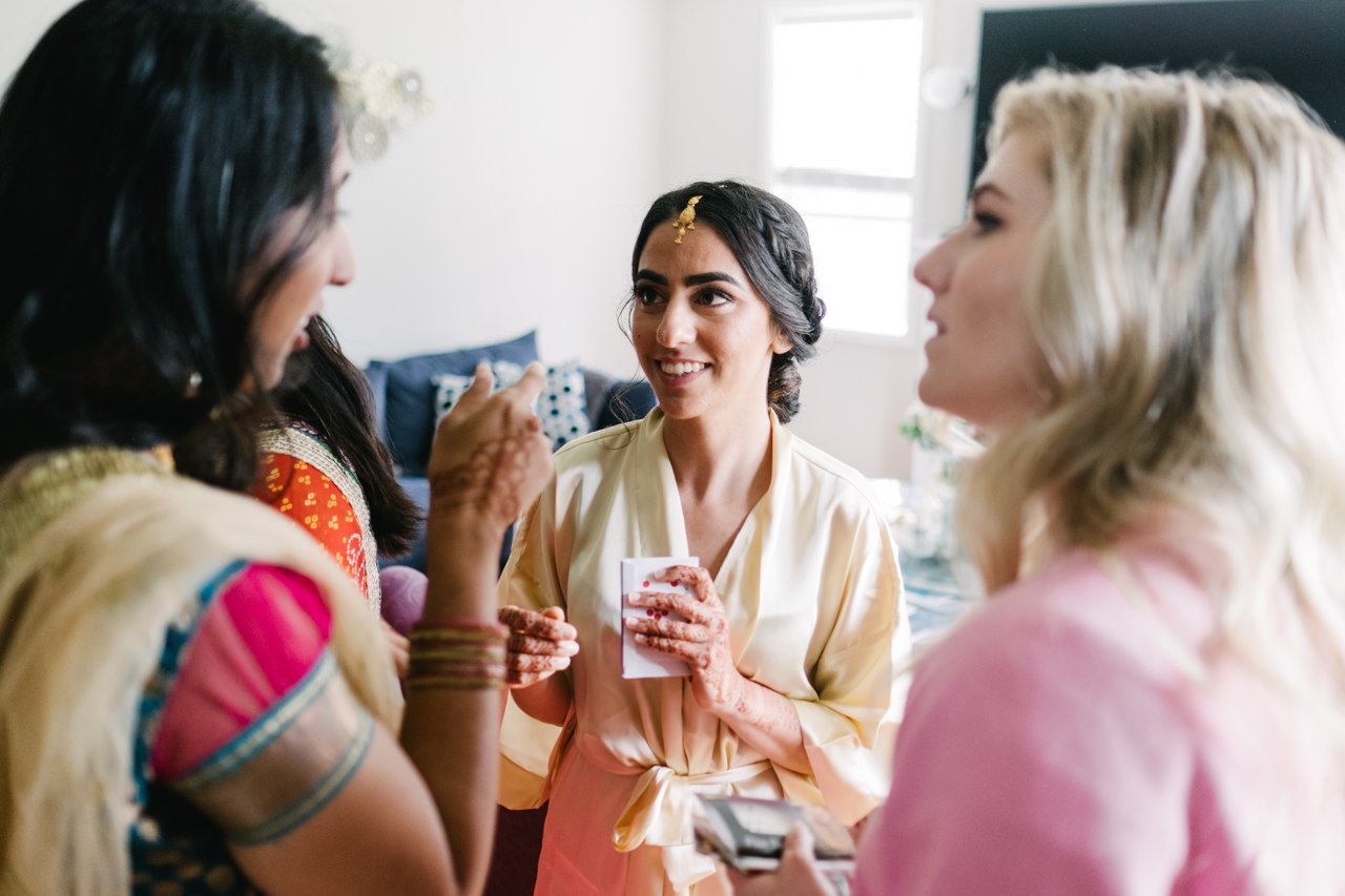  Bride talks with bridesmaids while getting ready 