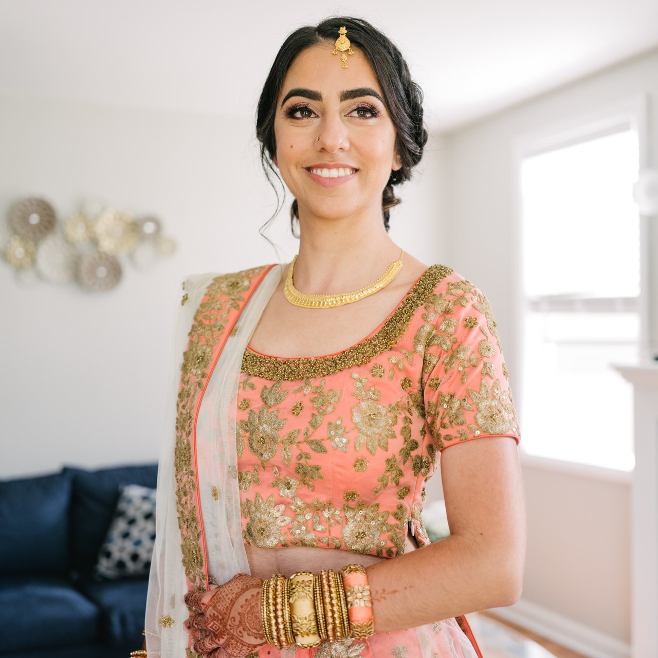 Window light portrait of bride in orange pink sari and gold jewelry 