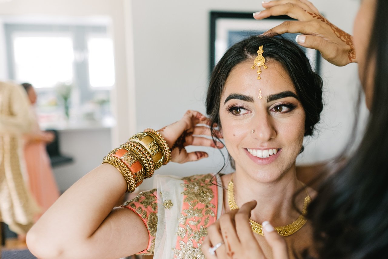  Bride has tikka hairpiece adjusted while getting ready for ceremony 