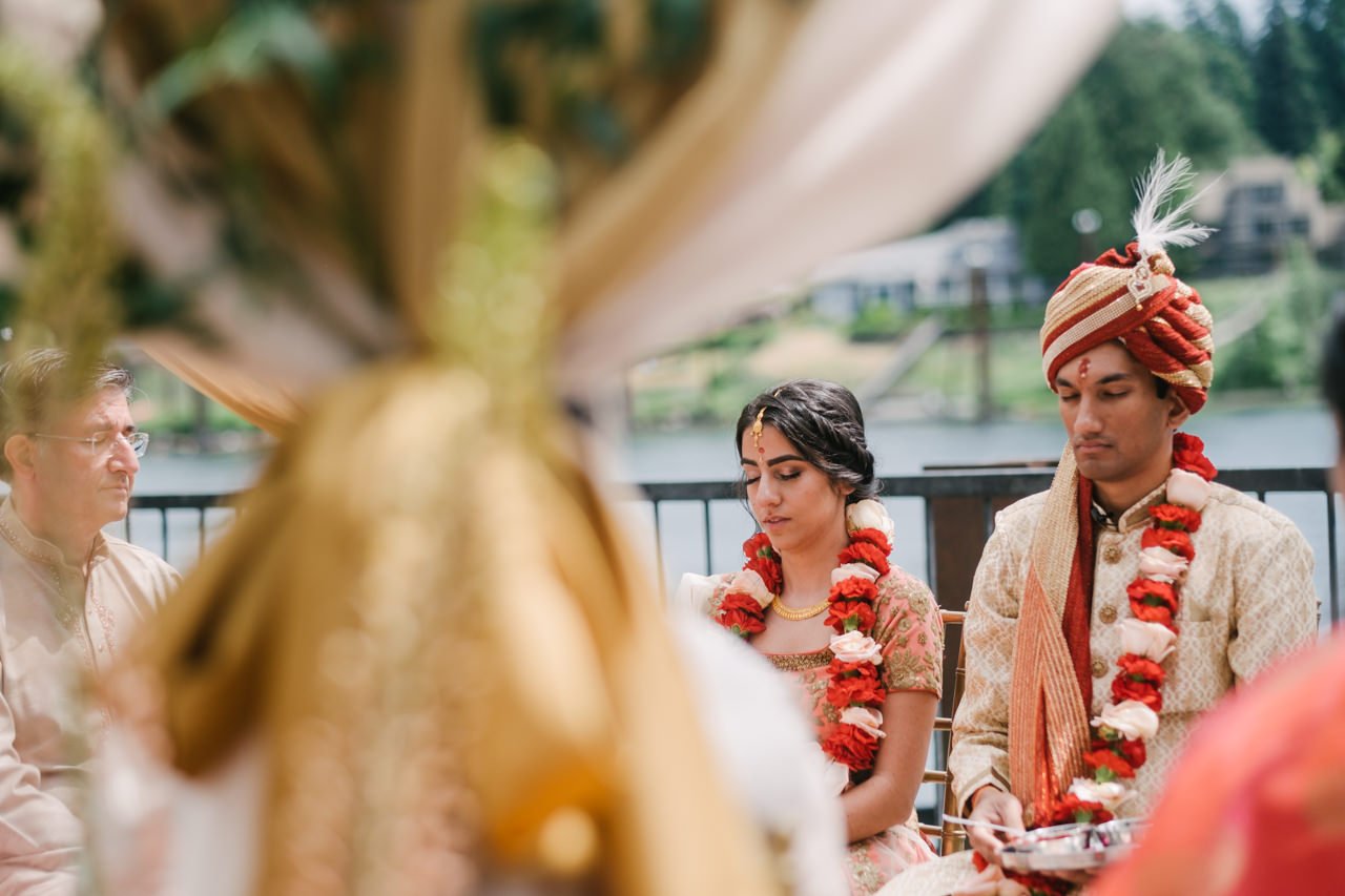  Bride and groom close eyes through gold mandap 