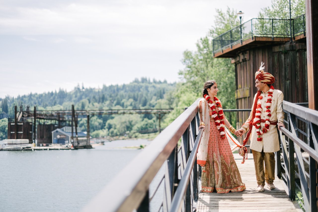  Indian couple holds hands on boat dock by willamette river 