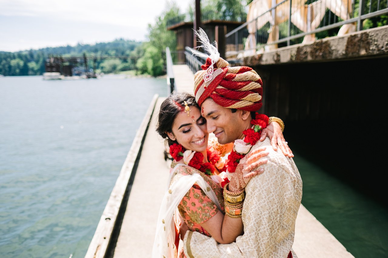  Colorful candid photo of Indian bride and groom embracing by river 