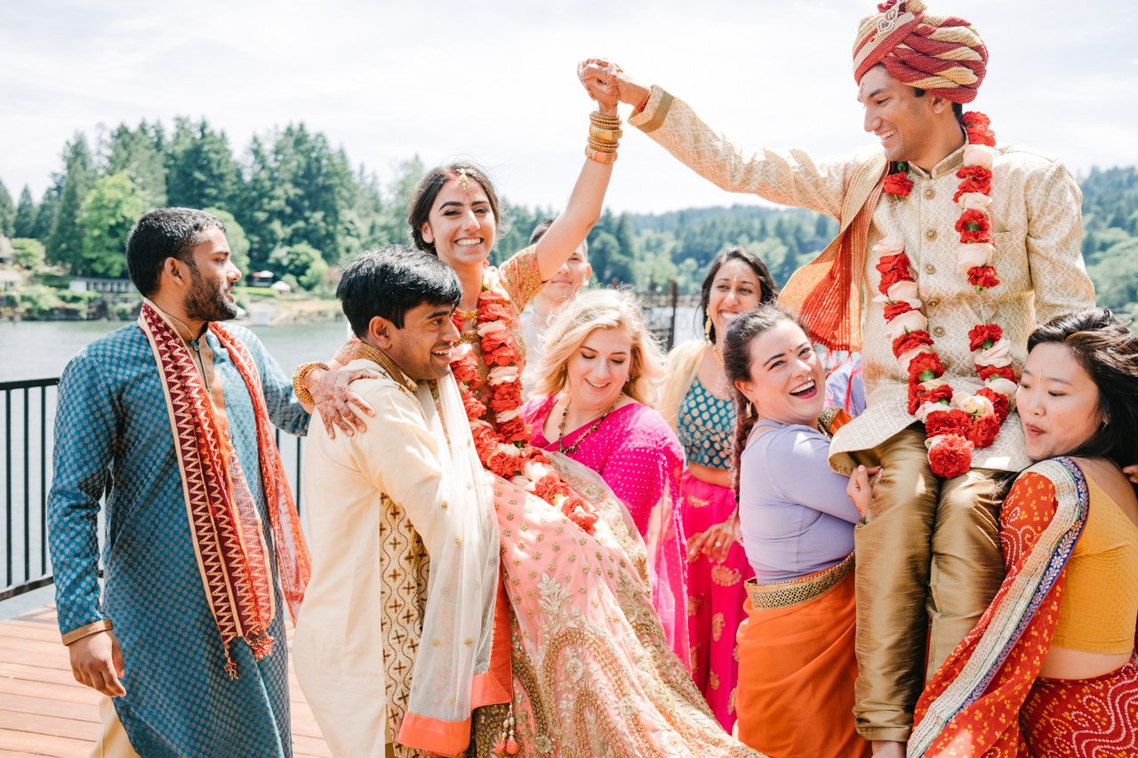  Colorful photo of bride and groom holding hands while bridal party lifts them in air 