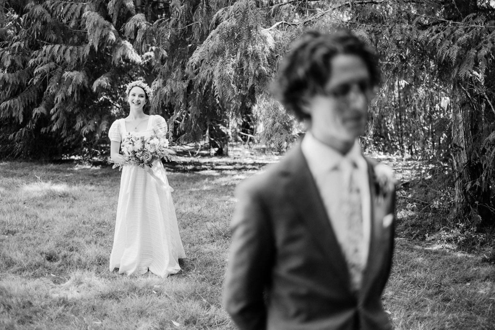  Bride with flower crown approaches groom waiting for first look 