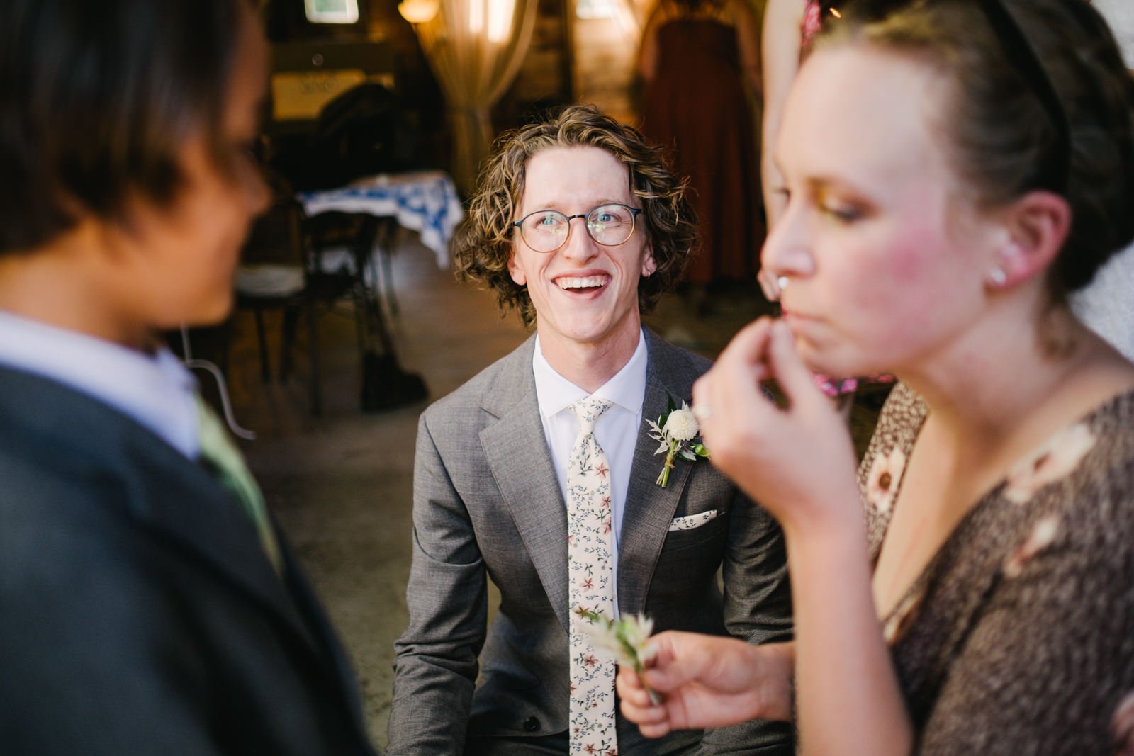  Groom laughs at ring bearer getting boutonniere pinned on jacket 
