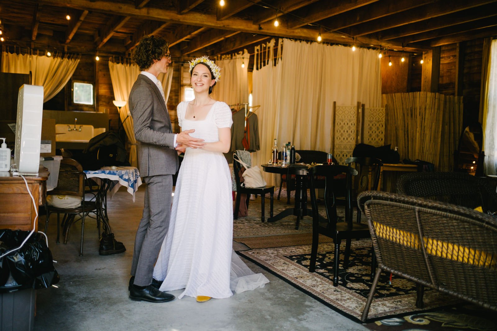  Bride and groom laugh with each other in room with wicker furniture 