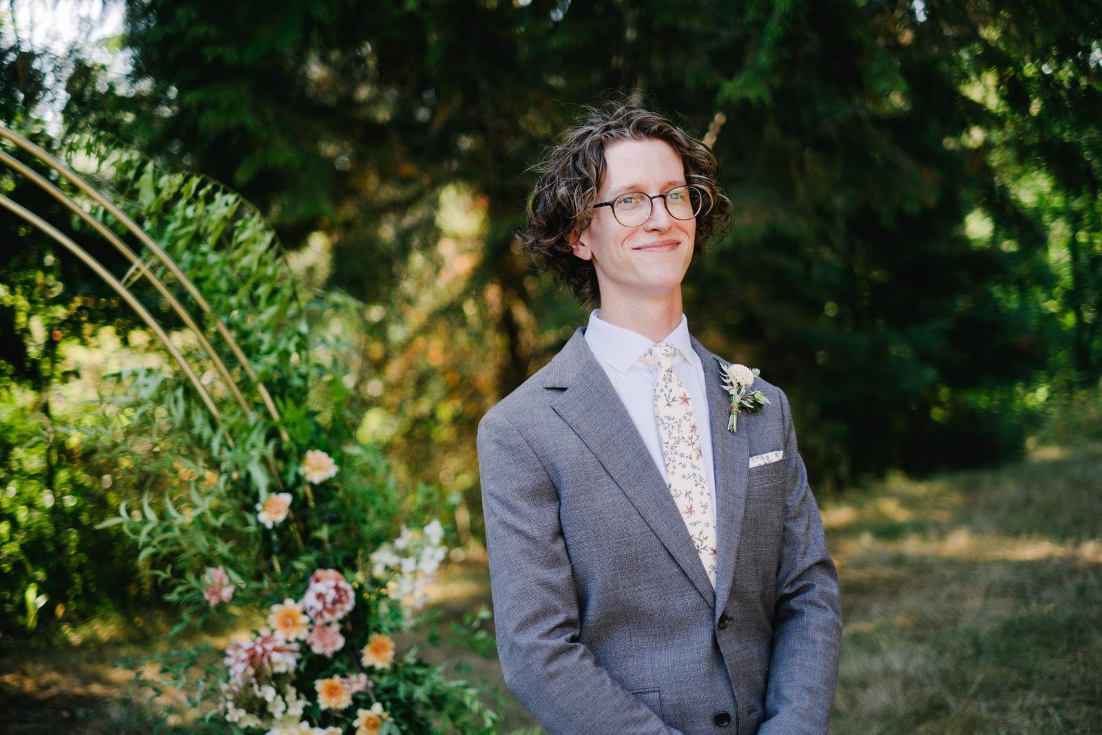  Groom in grey suit and yellow floral tie smiles while waiting for bride down the aisle 