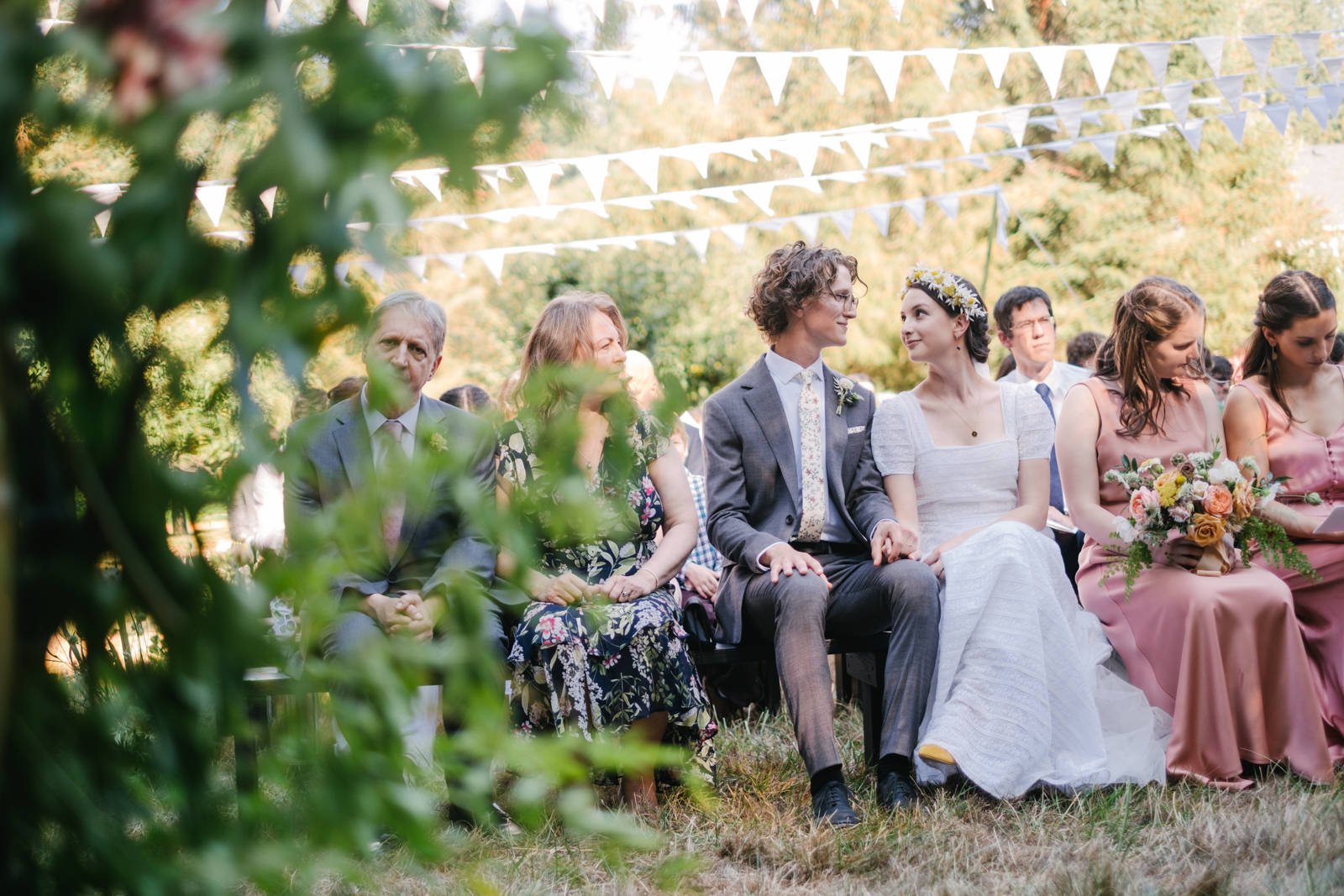  Bride and groom sit with wedding guests during ceremony while hymns are sung 