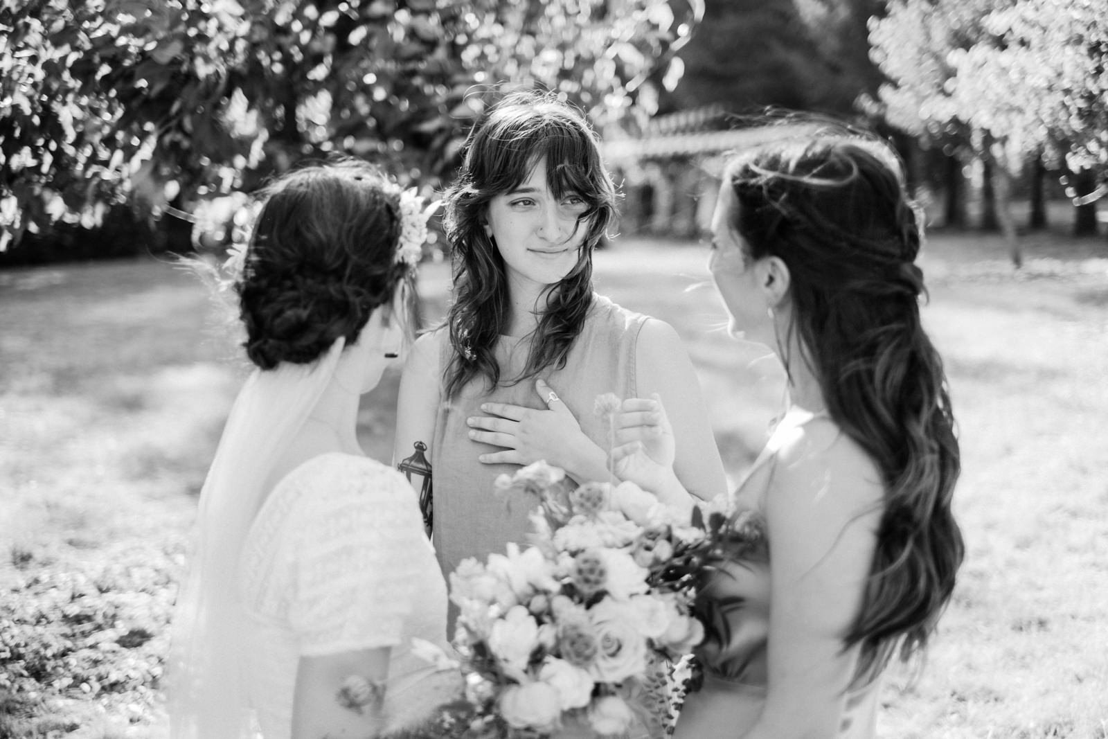  Bridesmaid kisses bride in celebration in sunshine 