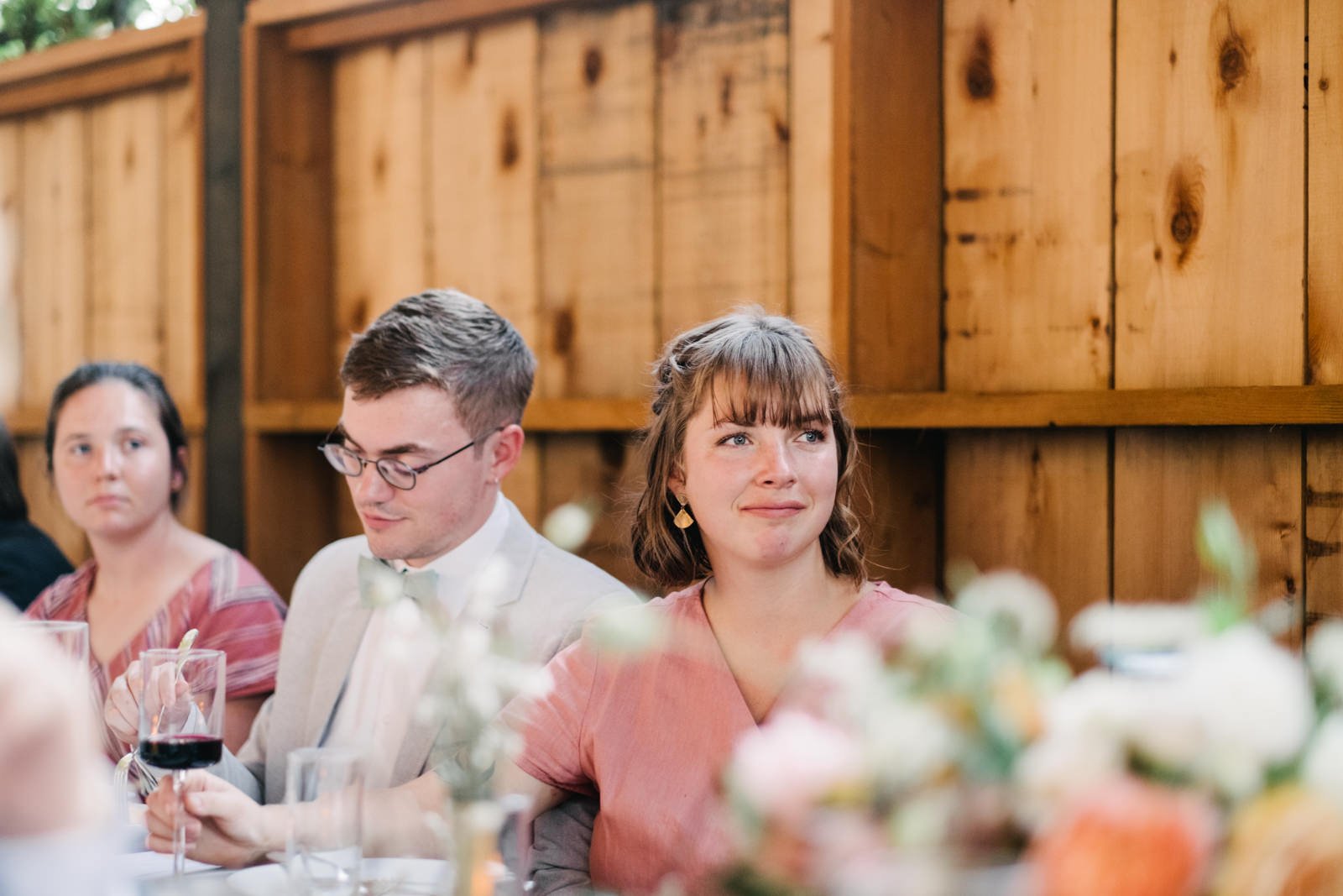  Bridesmaid listens to sad toasts with wood backdrop 