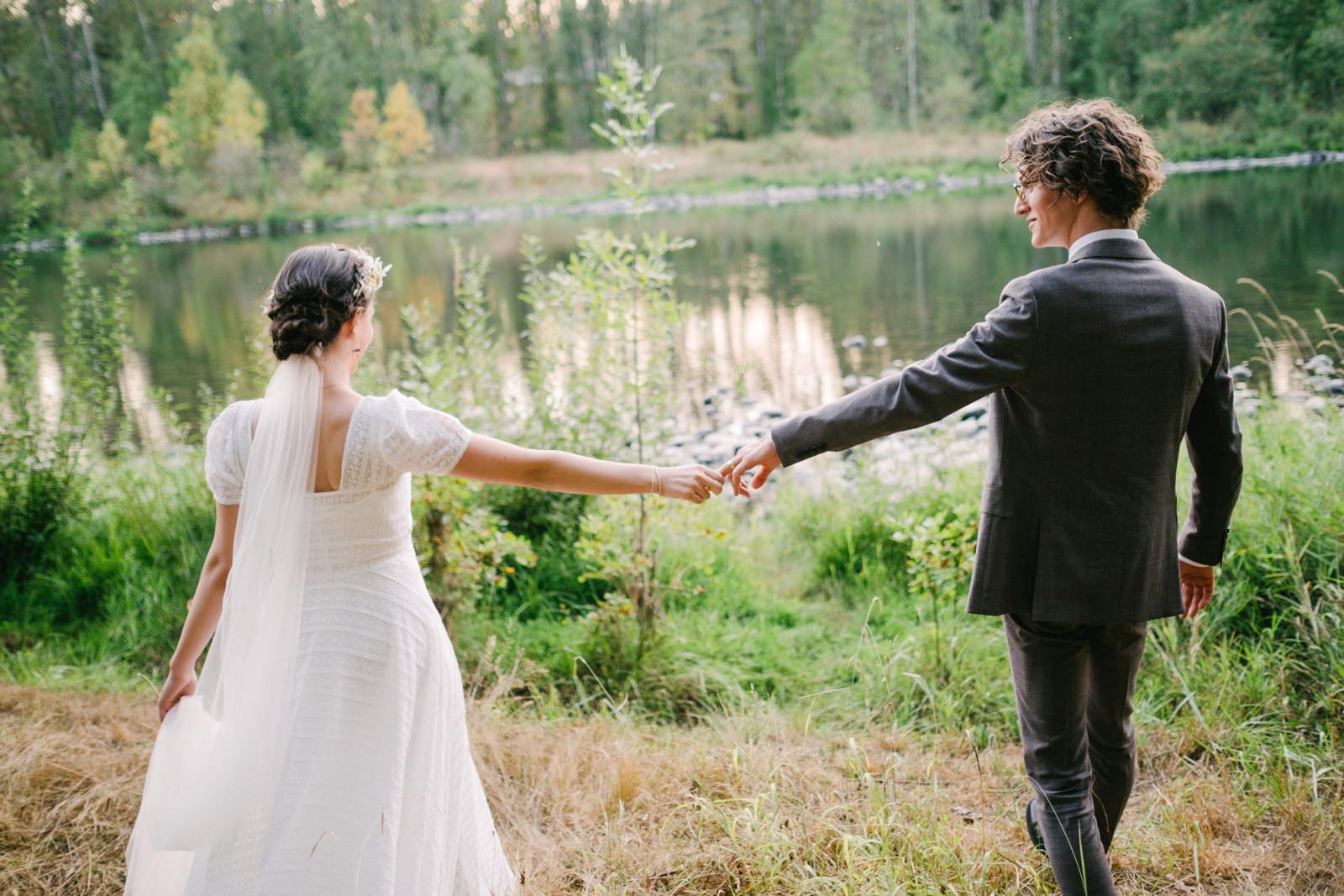  Bride and groom hold hands at river entrance 