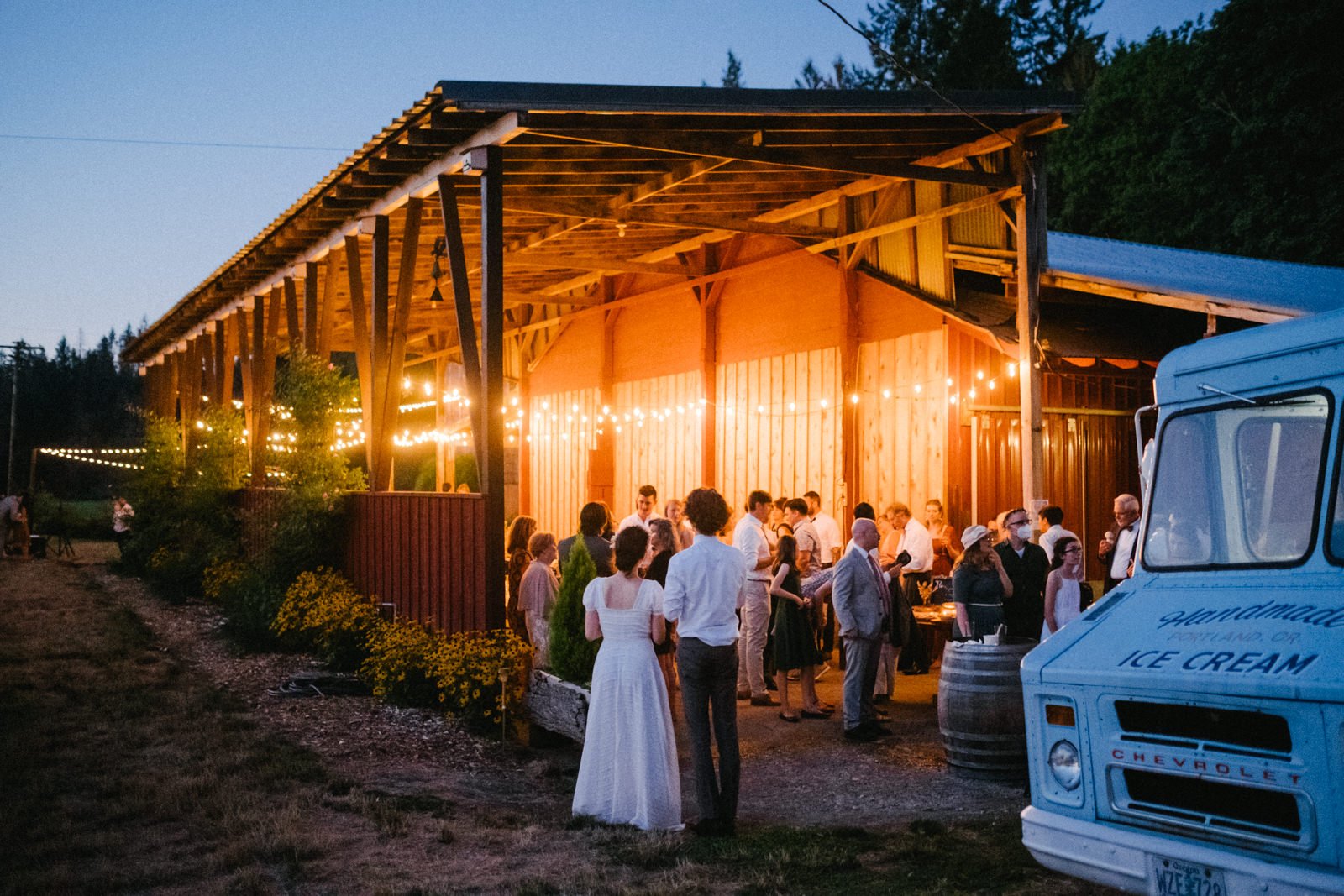  Couple looks on their wedding reception with twinkle lights and an ice cream truck 