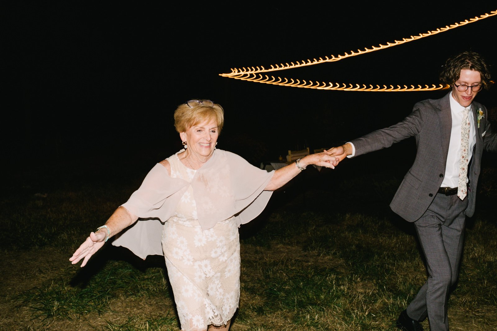 Groom holds hand of grandmother during reception dancing 