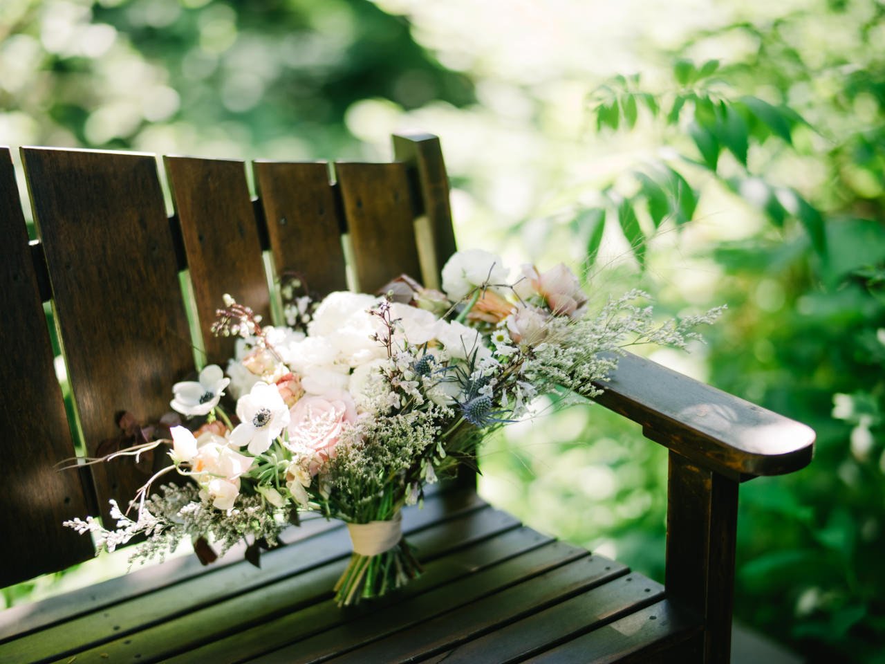  Bridal bouquet sits on wooden bench with thistle rose and natural florals 