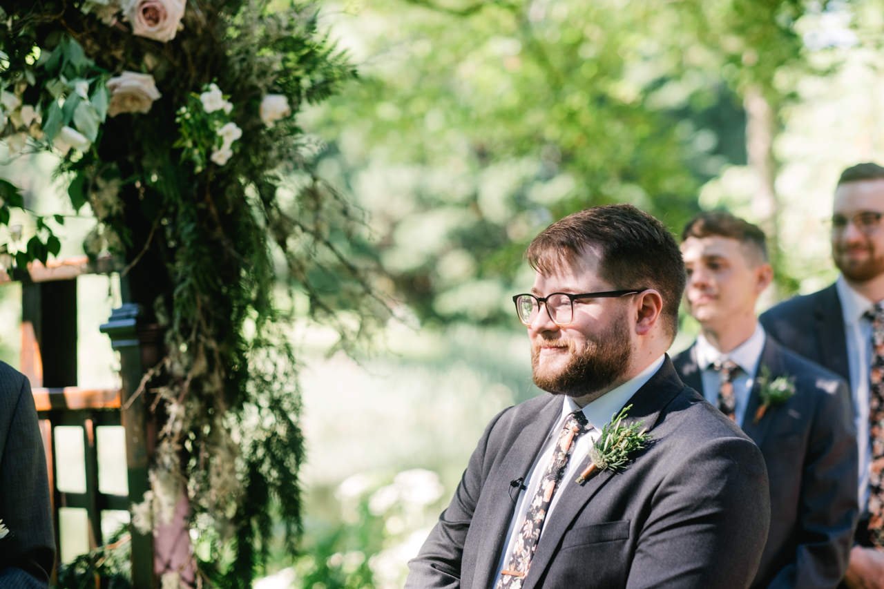  Close up of groom smiling in sunlight in floral tie 