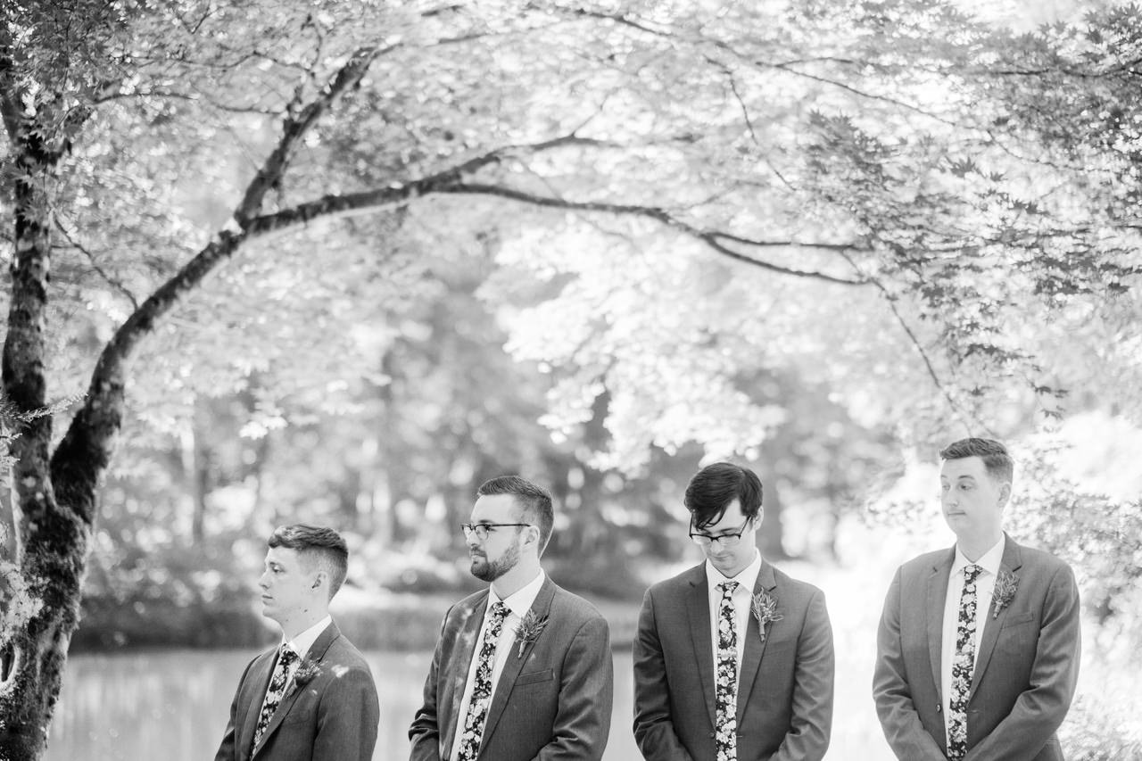  Groomsmen stand together under arch of tree 