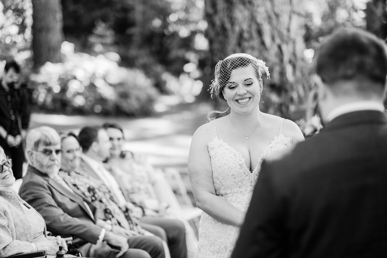  Bride smiles in black and white photo listening to vows 