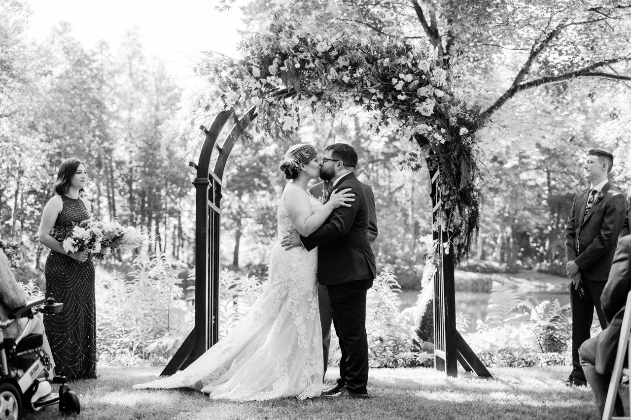  Black and white photo of couple kissing at end of wedding ceremony 