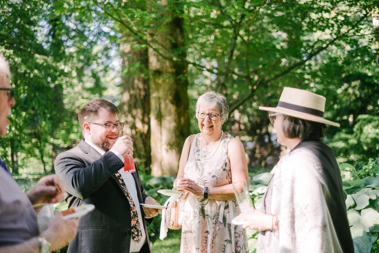  Mother of groom shares laugh with groom and guests in sunlight 