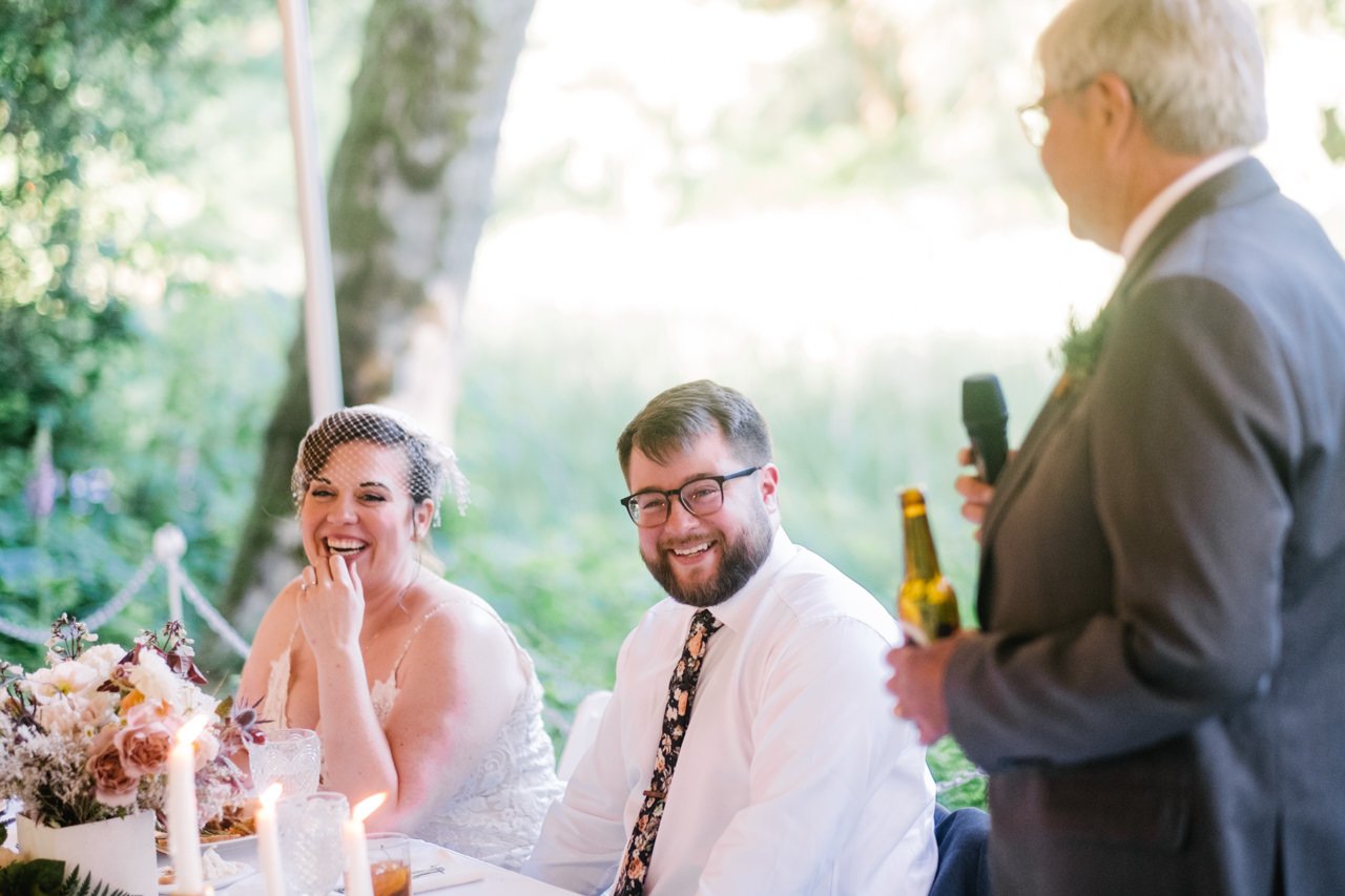  Groom and bride laughing during toast by father 