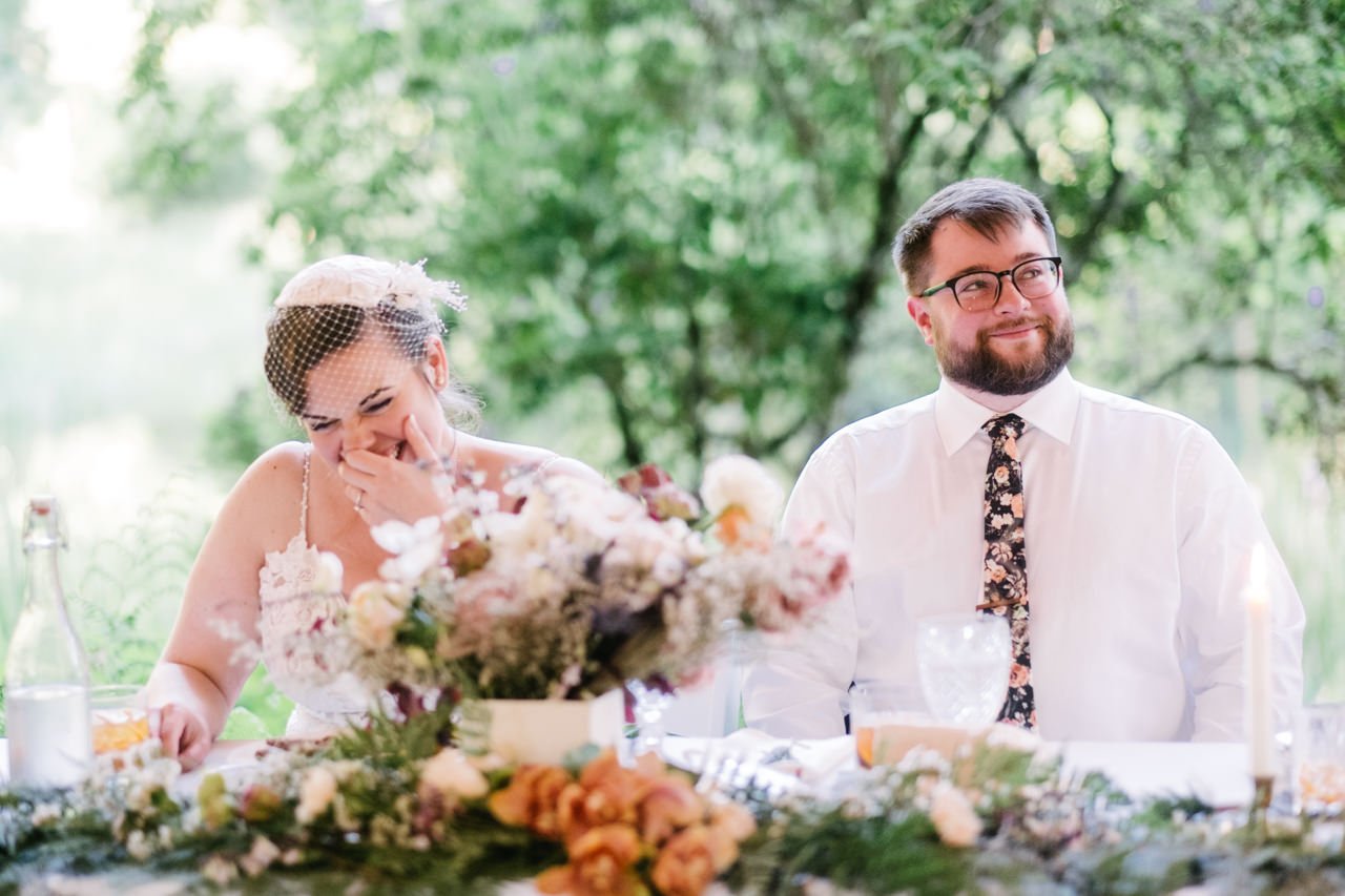  Bride giggles behind orange and pink floral table 