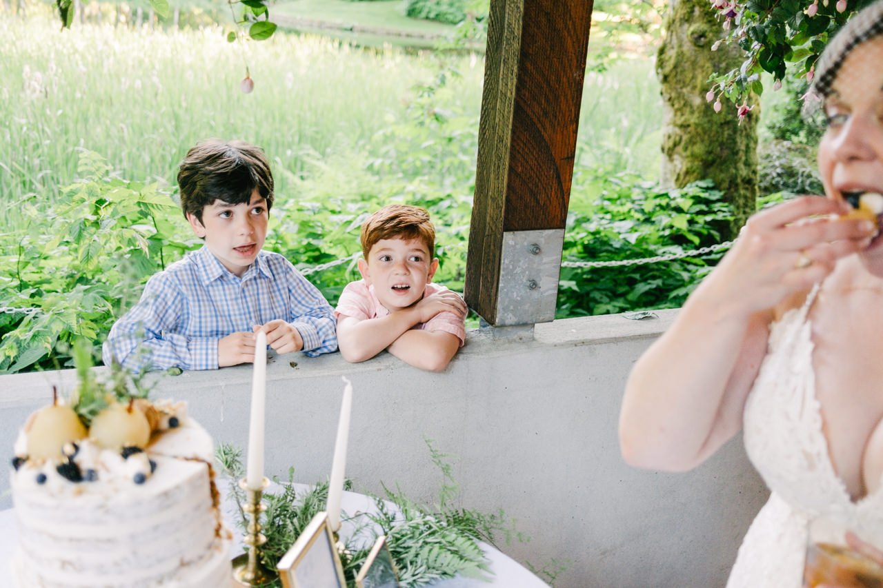  Two boys look longingly at bride eating delicious cake in Candid moment 