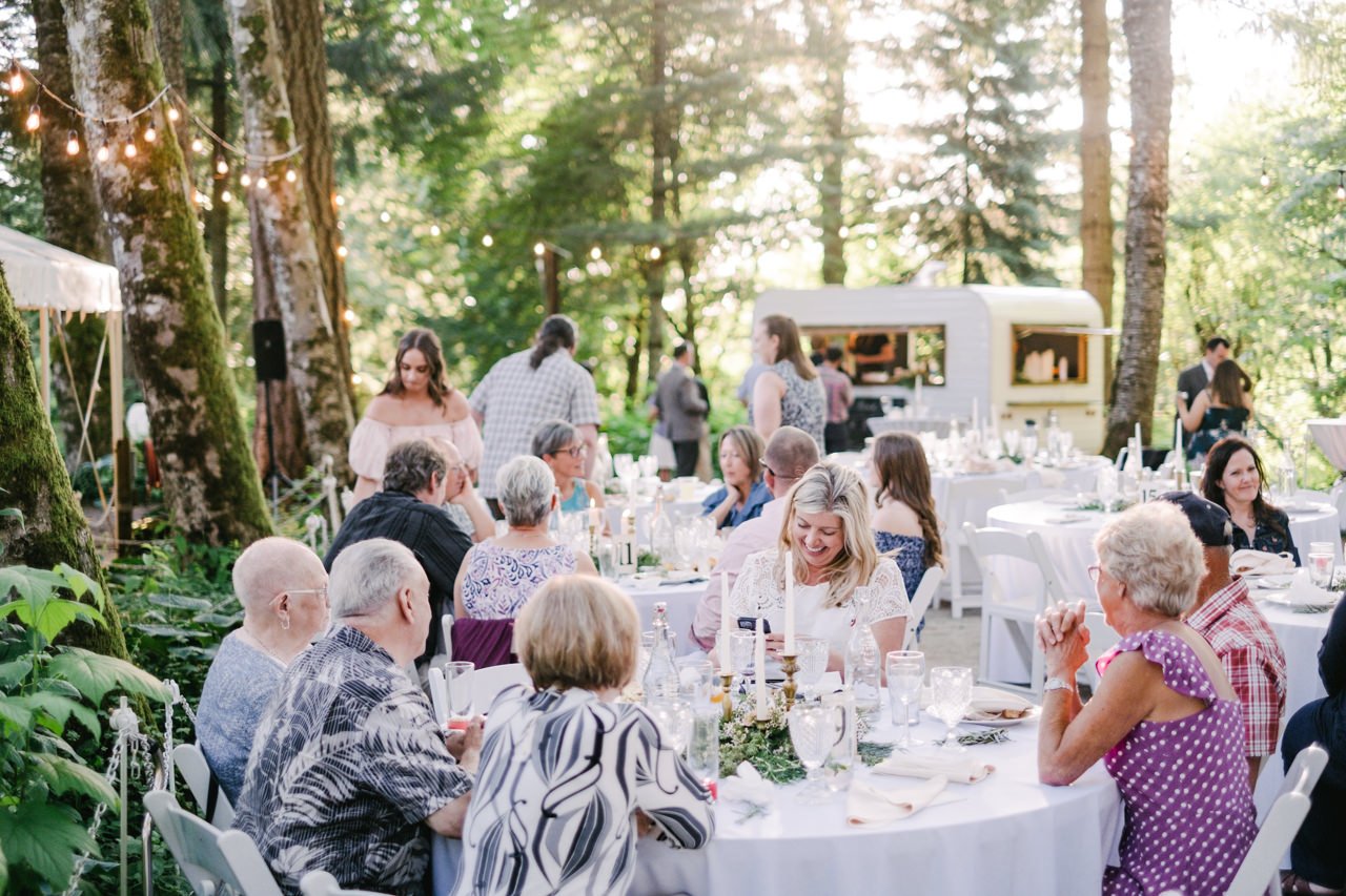  Wedding guests laughing at white tables with tiddly trailer behind them 