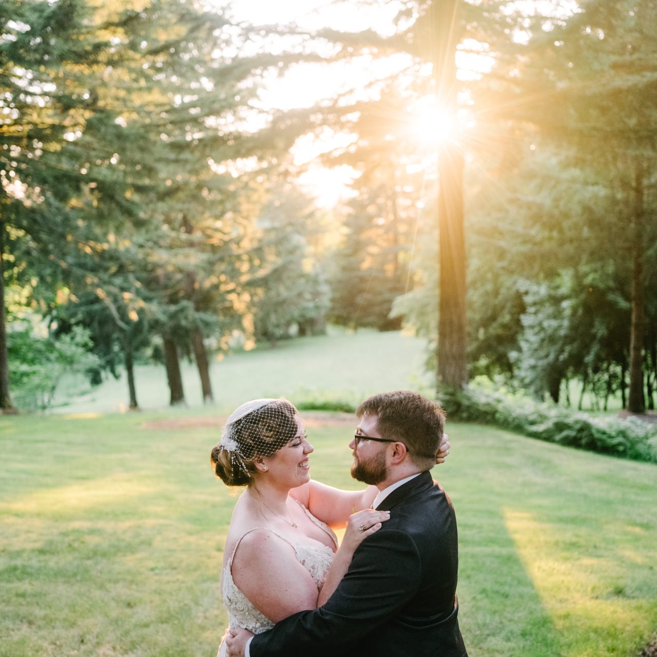  Square photo of bride and groom laughing in sunlight field and tall fir trees 