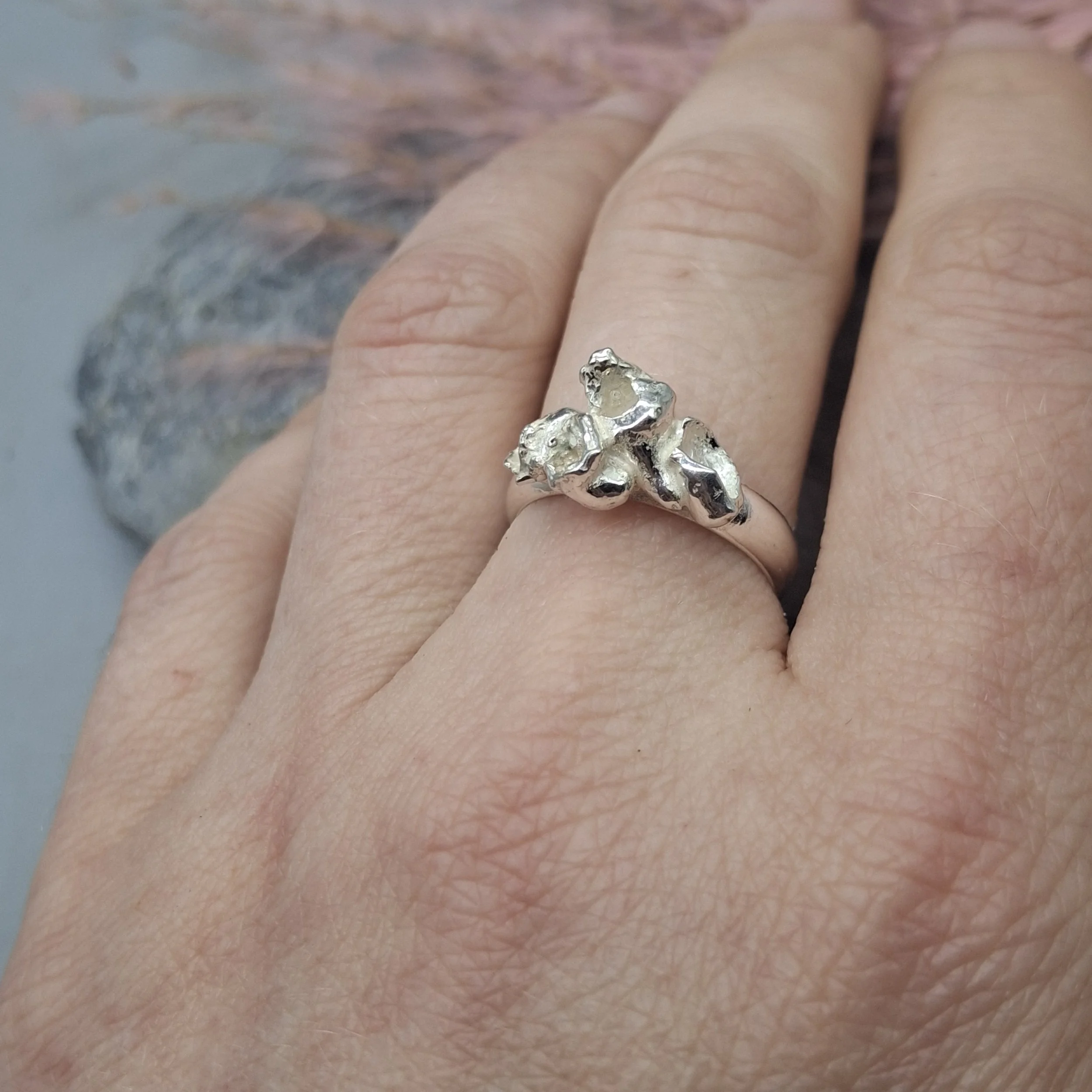 Handmade sterling silver Fallen Blossom ring with organic water-cast petal textures, inspired by fallen cherry blossom, with no gemstone, shown worn on the hand