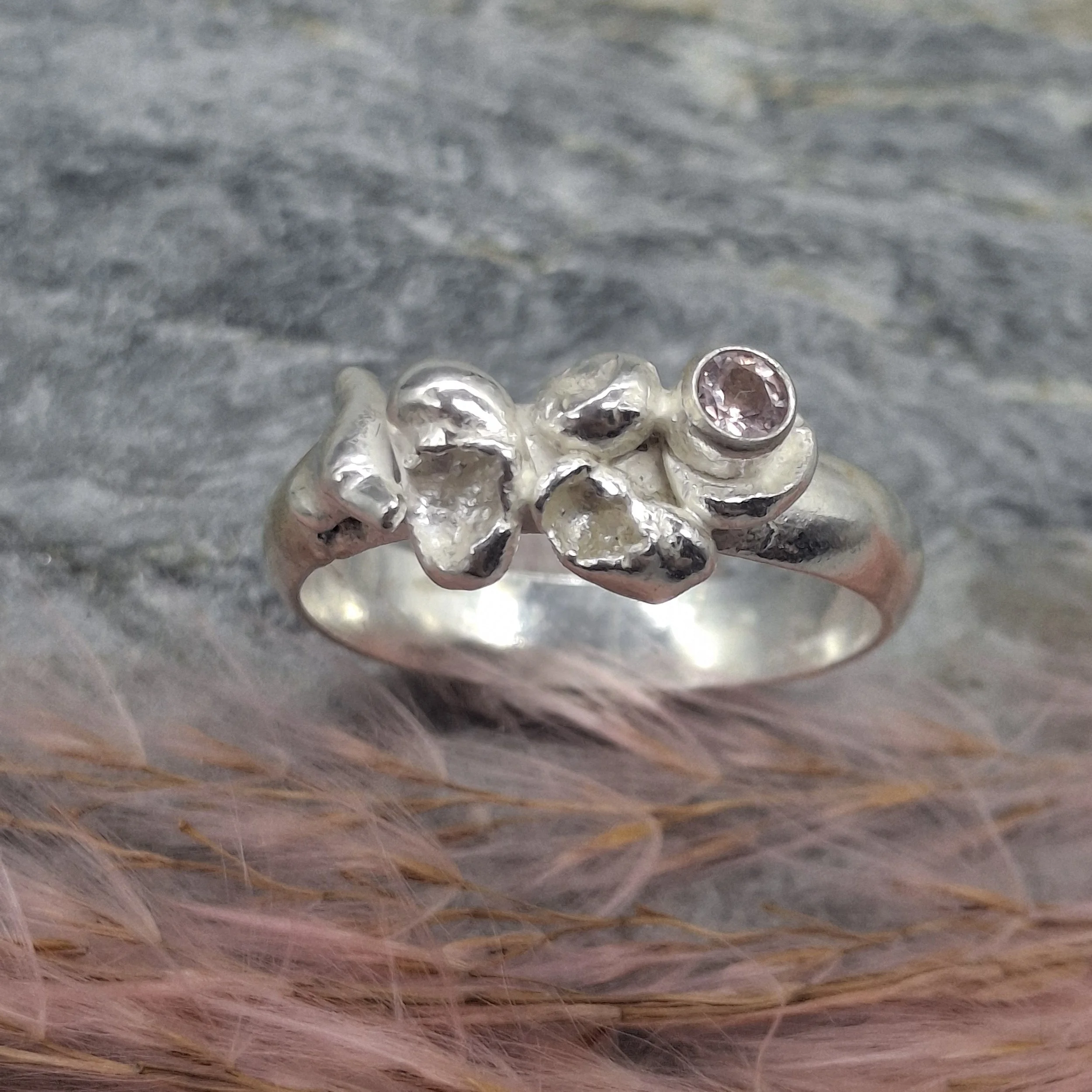 Handmade sterling silver Fallen Blossom ring with water-cast petal textures, featuring a pale pink tourmaline nestled in organic silver.