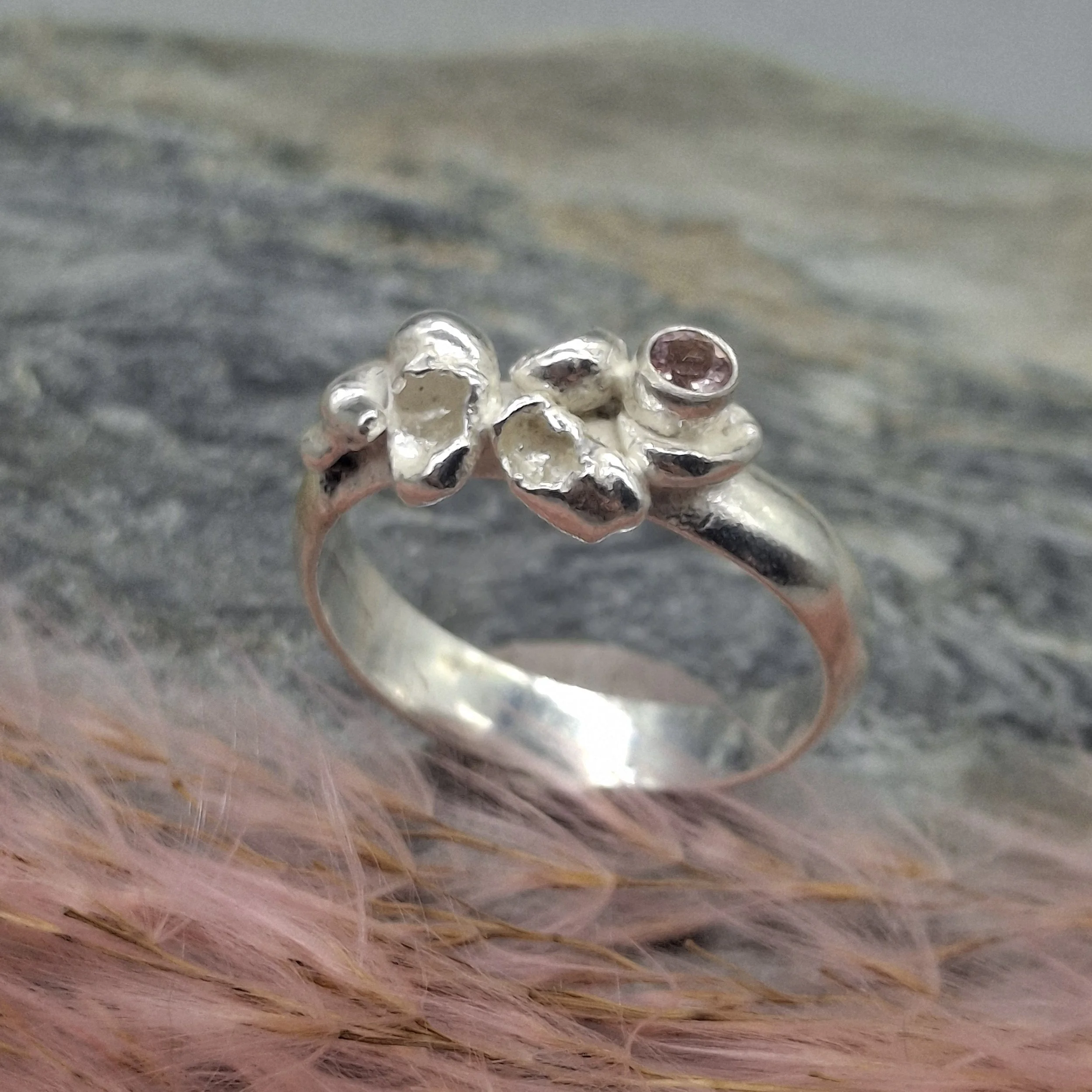 Handmade sterling silver Fallen Blossom ring with water-cast petal textures, featuring a pale pink tourmaline nestled in organic silver.