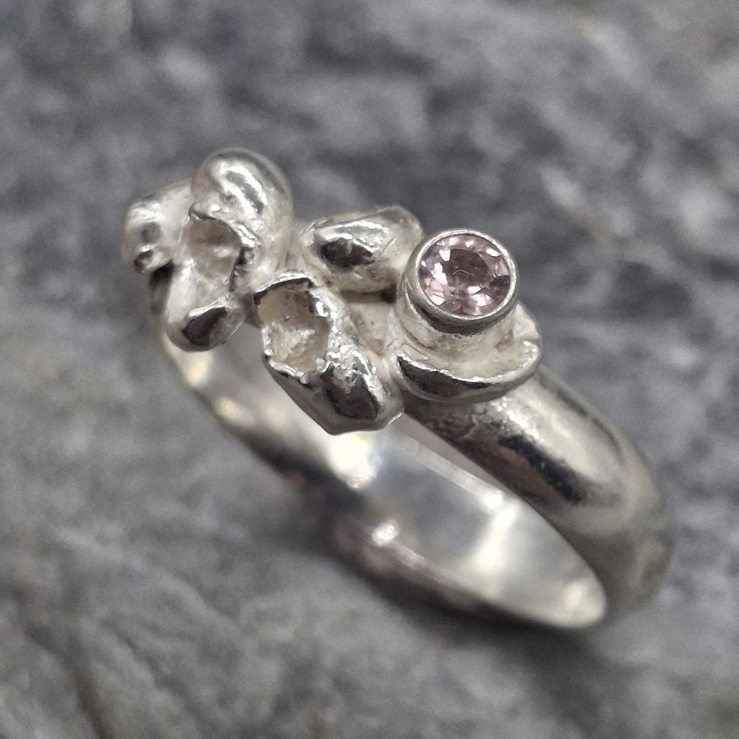 Handmade sterling silver Fallen Blossom ring with water-cast petal textures, featuring a pale pink tourmaline nestled in organic silver.
