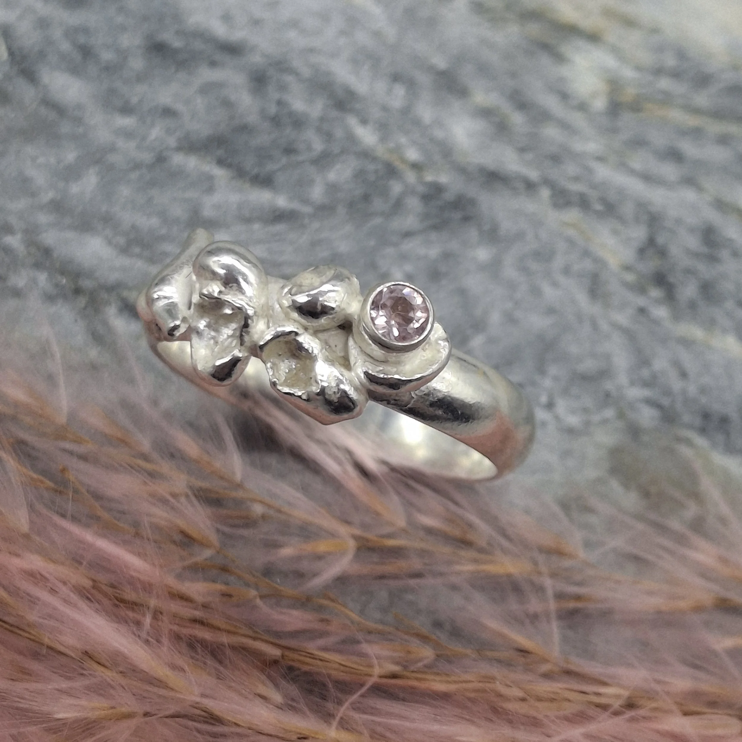 Handmade sterling silver Fallen Blossom ring with water-cast petal textures, featuring a pale pink tourmaline nestled in organic silver.